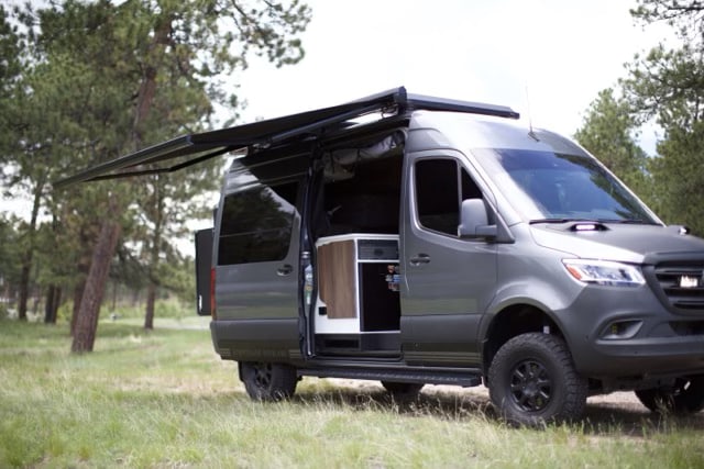  with a side step visible. Ready for adventure!|Front view of a rugged dark gray Mercedes-Benz Sprinter RV rental van with auxiliary lights and off-road tires — photo 6
