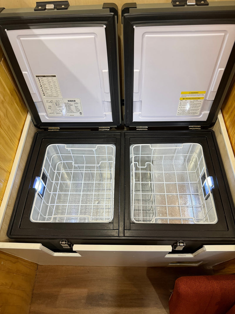 Opened dual-zone ICECO fridge/freezer for an rv rental, showing empty baskets, internal lights, and food temp guides on the lids. — photo 16