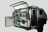 This RV rental features a compact camper with its side open, revealing an organized outdoor kitchen and supplies.