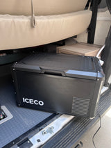 A black ICECO portable fridge/freezer neatly placed inside an RV rental, ready for adventure and keeping items cool.