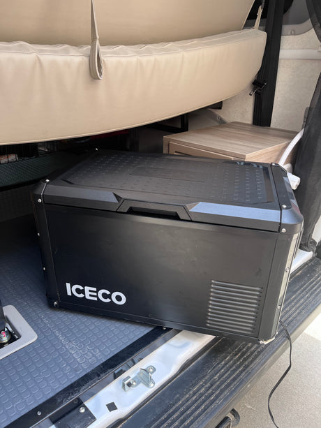 A black ICECO portable fridge/freezer neatly placed inside an RV rental, ready for adventure and keeping items cool.