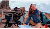 Woman takes selfie by an RV rental camper van & trailer in a rocky desert. Ideal for outdoor adventure and road trips!