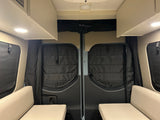 Cozy rv rental interior looking towards the rear doors. Features include quilted insulation, overhead cabinets, and two bench seats.