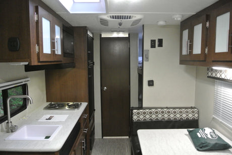 Compact RV rental interior featuring a full kitchen, dinette area, and comfortable living space for travel.