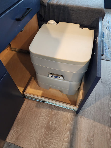 This RV rental features a portable toilet neatly stored in a pull-out drawer, maximizing space efficiently.