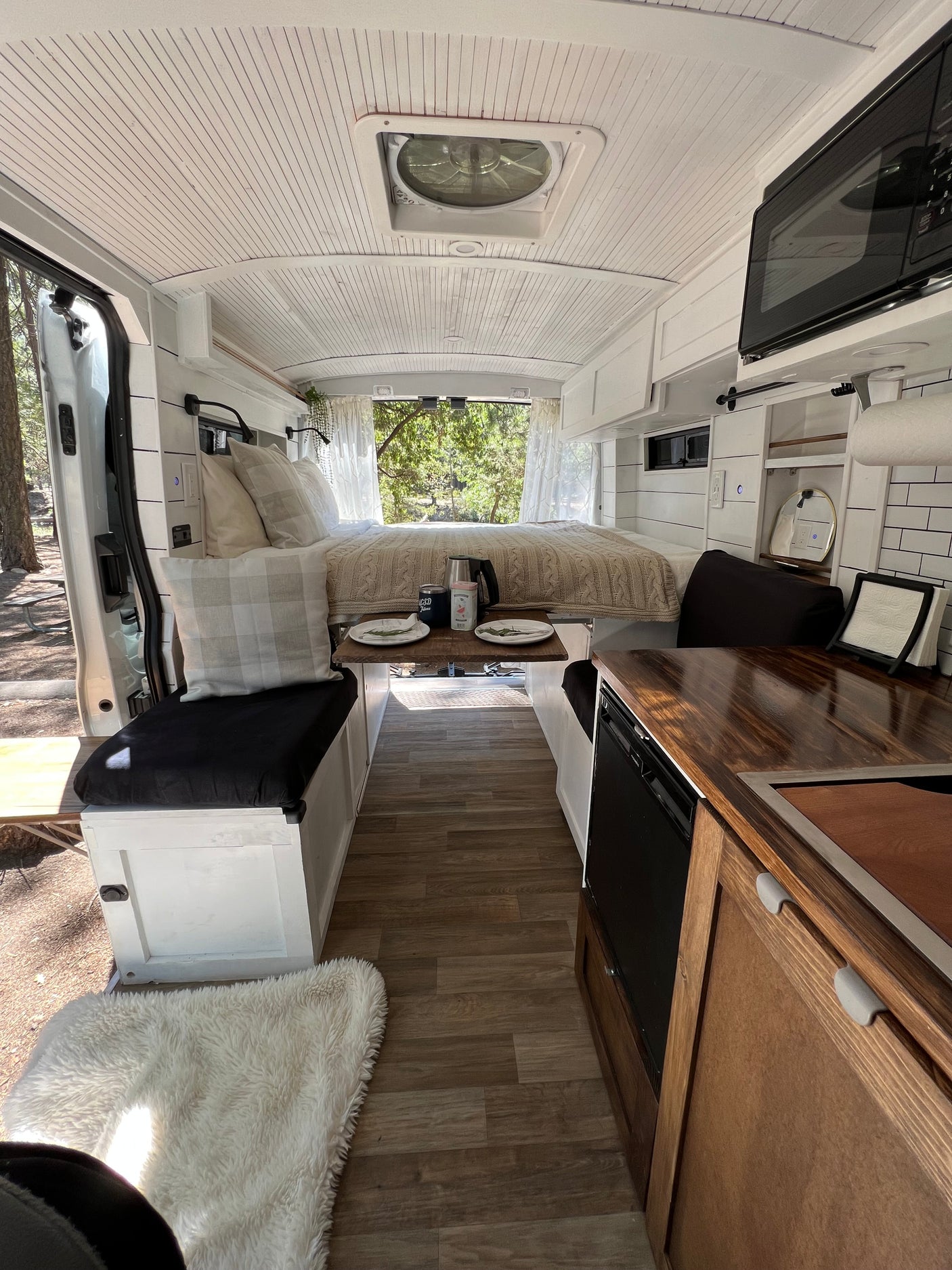 Cozy and well-equipped RV rental interior with bed, kitchen, dinette, and wood-look floors, perfect for adventurers.