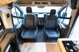 RV rental van interior featuring front swivel captain's chairs, a modern dashboard, and a glimpse of the integrated kitchen.