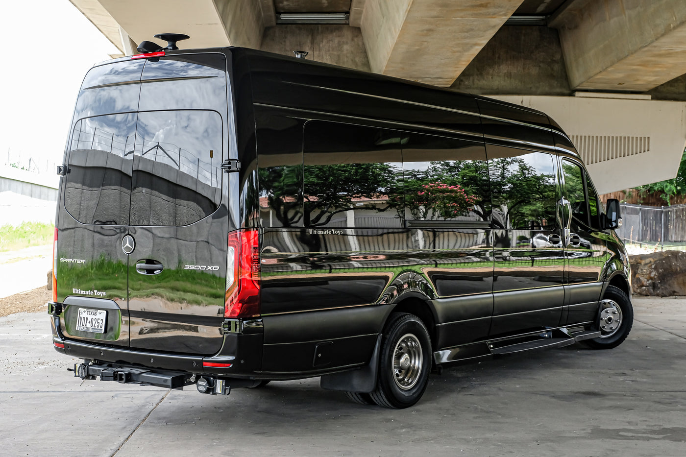 Sleek black Mercedes Sprinter luxury RV rental van, reflecting the overpass and trees, parked underneath. — photo 10