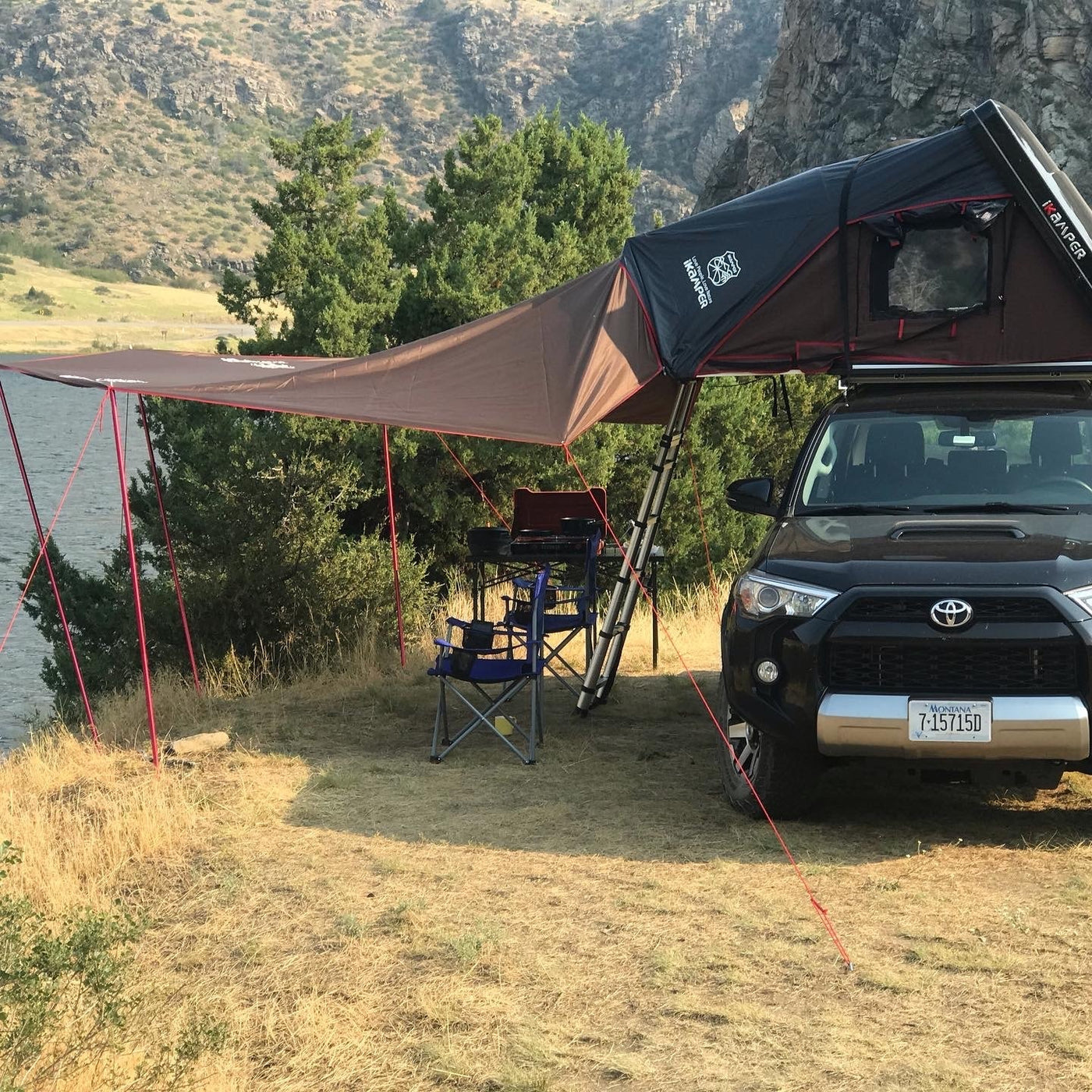 Black SUV with iKamper rooftop tent and awning set up for scenic lakefront camping. Perfect for your next rv rental adventure. — photo 6