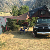 Black SUV with iKamper rooftop tent and awning set up for scenic lakefront camping. Perfect for your next rv rental adventure.