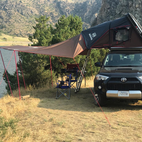 Black SUV with iKamper rooftop tent and awning set up for scenic lakefront camping. Perfect for your next rv rental adventure.
