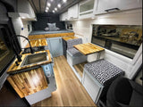 Explore this modern RV rental interior featuring a full kitchen with wood counters, comfortable dining area, and cozy bed.