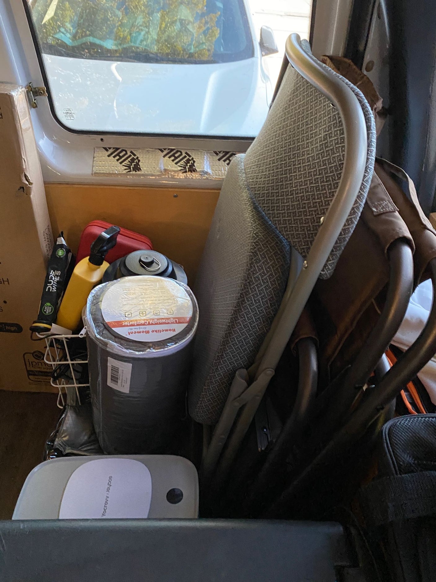Inside an RV rental, packed with travel essentials: foldable chair, comforter, and gear, ready for an adventure.