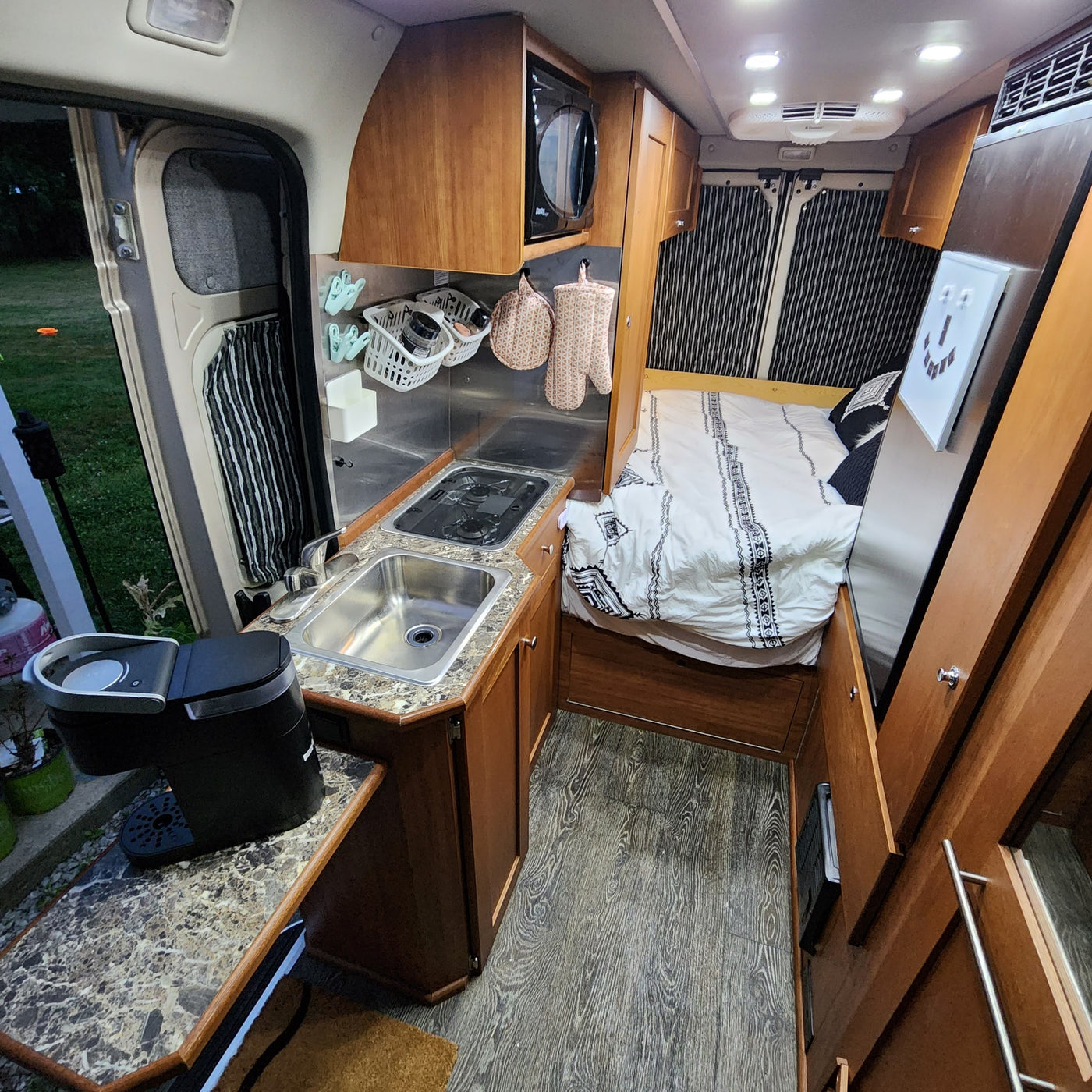  and a built-in wooden table for travel convenience.|This rv rental features a spacious front cabin with two comfortable seats and an accessible fire extinguisher by the passenger floor.|Spacious rv rental interior features warm wood cabinetry — photo 10