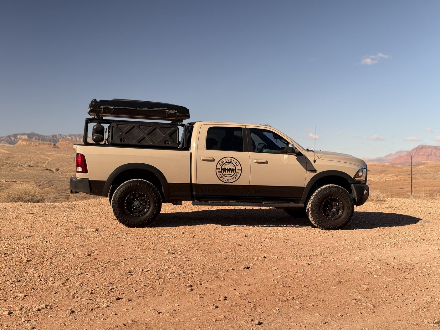 A beige and black overland truck with a rooftop tent, perfect for an off-road RV rental expedition.