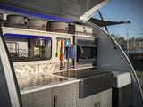 Sleek outdoor camper kitchen in an RV rental, showing a sink, microwave, and organized storage for camping trips.