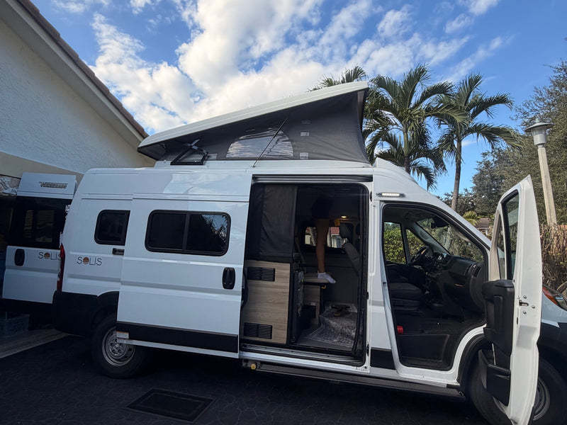  is parked in a driveway beside a house and palm tree.|This white RV rental — photo 4