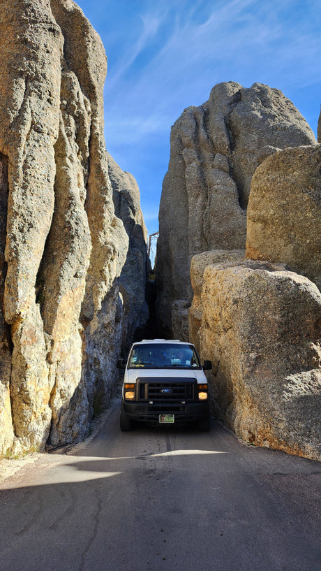 Experience a unique road trip! This RV rental navigates a dramatic, narrow rock canyon under a clear blue sky.