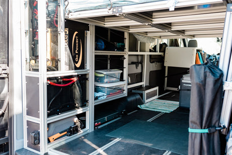 Interior of a custom RV rental van, showcasing a power system, modular storage, and camping amenities for adventures.