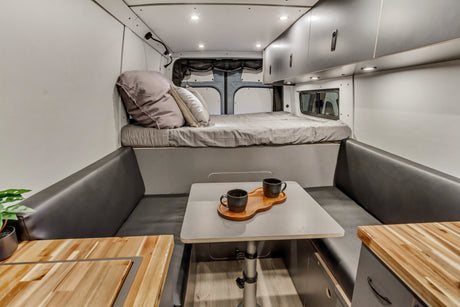 Modern rv rental interior with a comfy raised bed, dining table, and sleek overhead storage for adventurers.
