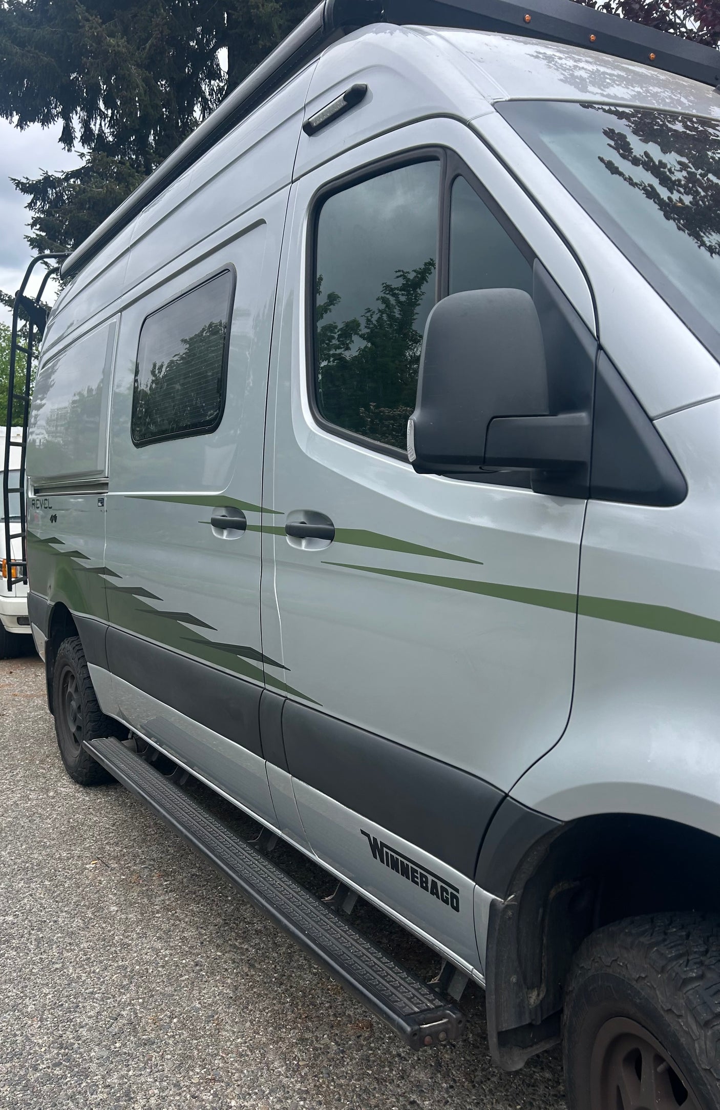 Silver Winnebago Revel adventure rv rental with distinct green decals, running boards, and a roof rack.