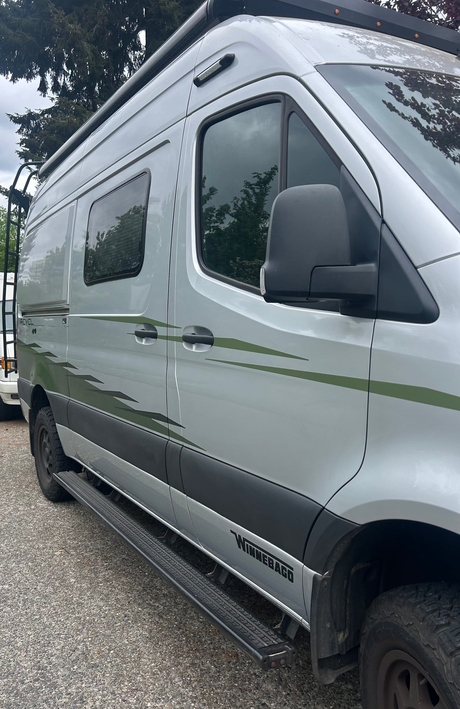 Silver Winnebago Revel adventure rv rental with distinct green decals, running boards, and a roof rack.