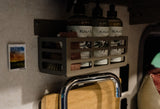Inside an RV rental: a wall caddy holds Koala Eco products above a sink with a cutting board, enhancing comfort.