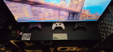 This RV rental's entertainment shelf features a TV, Xbox controllers, smartphone, and remotes, creating a cozy living area.