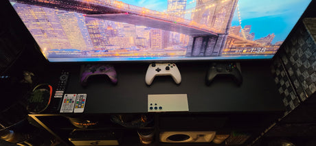 This RV rental's entertainment shelf features a TV, Xbox controllers, smartphone, and remotes, creating a cozy living area.