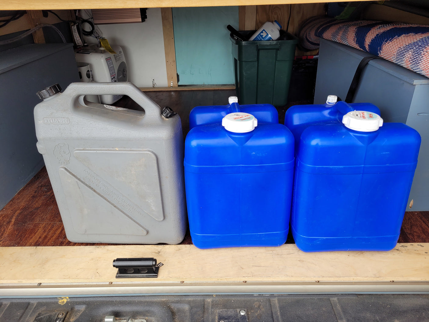 Portable water storage in an RV rental: Blue and grey Reliance containers ensure you stay hydrated on your adventures. Perfect for van life!