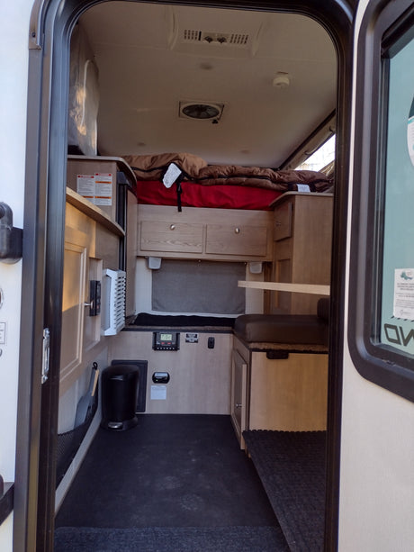 This RV rental interior offers a compact living space with a bed, dinette, and functional amenities.