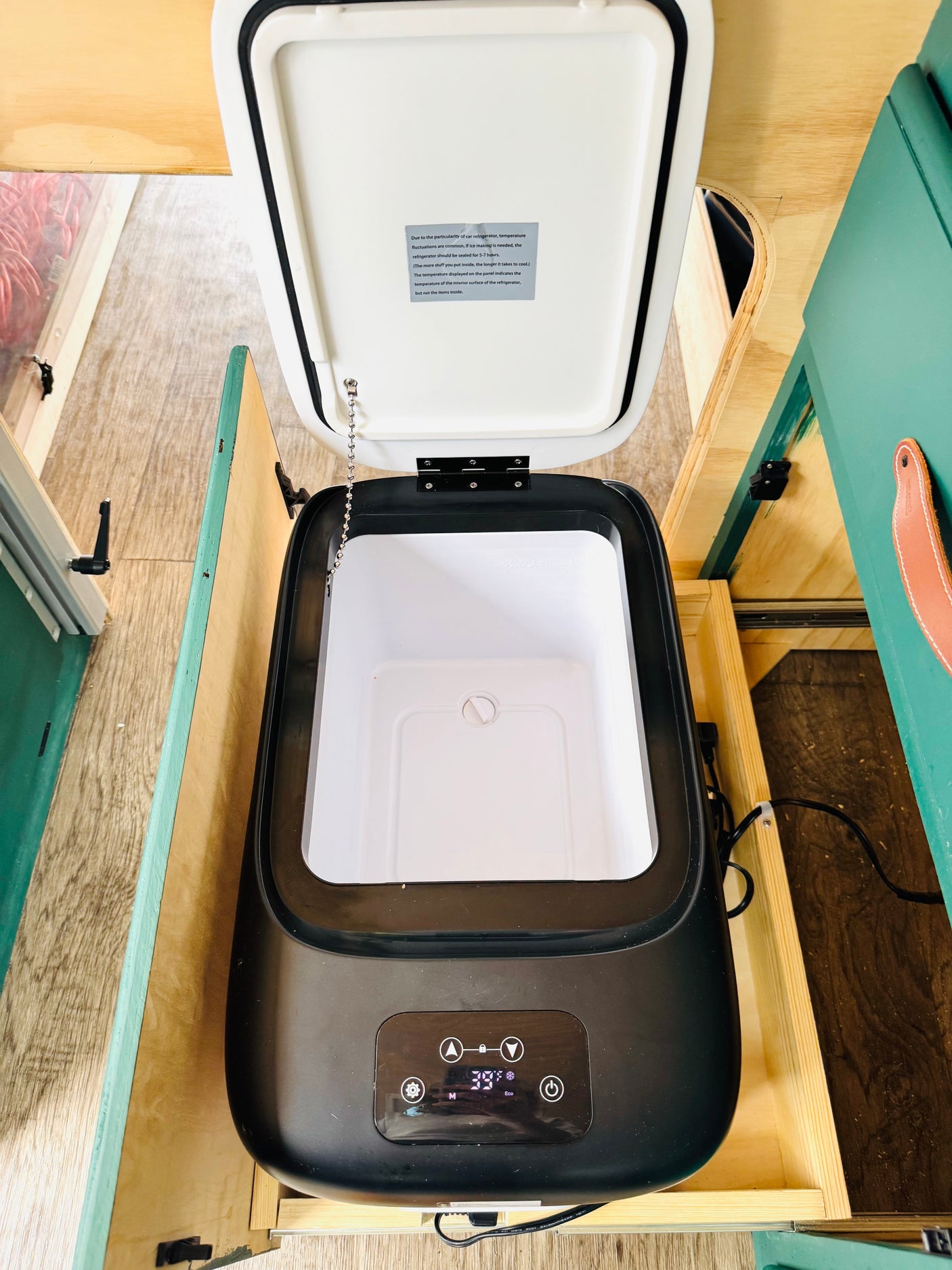 Open portable car refrigerator, set to 39°F, built into an RV rental. Note the temp display & info on fluctuations.