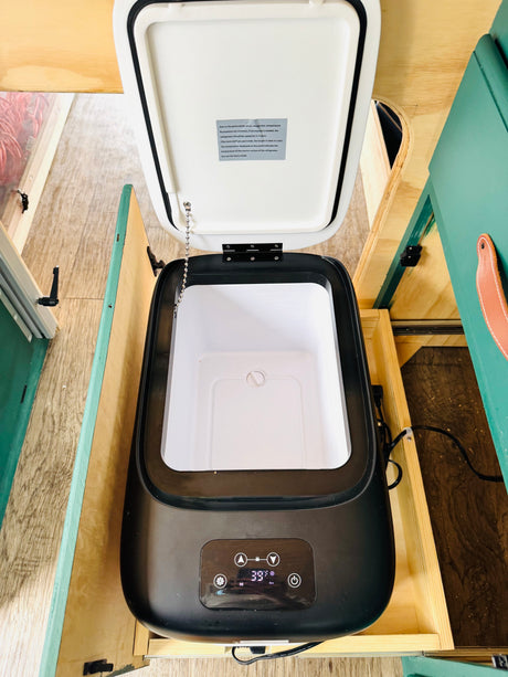 Open portable car refrigerator, set to 39°F, built into an RV rental. Note the temp display & info on fluctuations.
