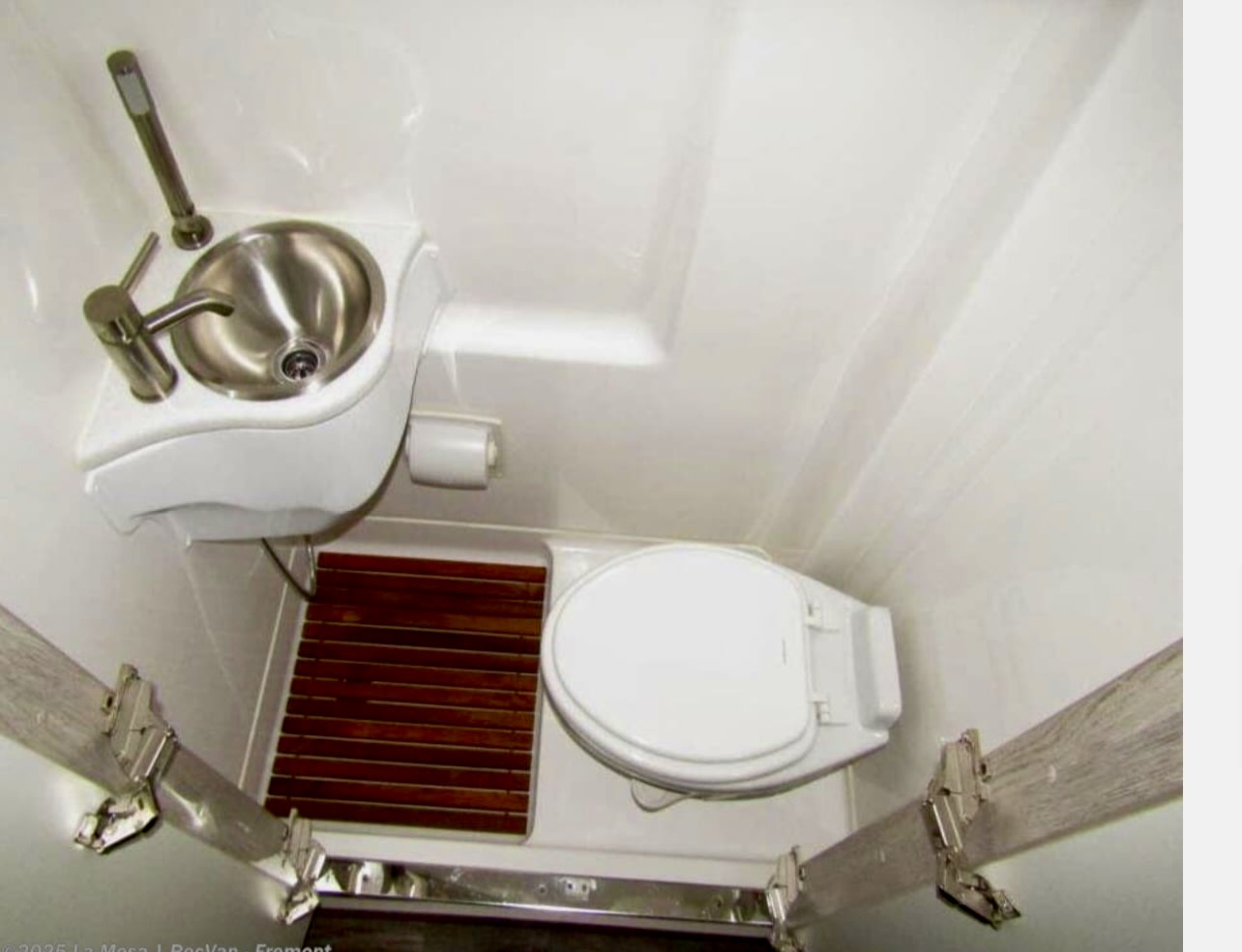 RV rental's compact wet bath features a sink, toilet, and pull-out shower. Efficiently designed for small spaces. — photo 5