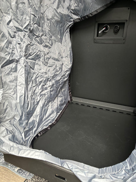 Inside a portable RV rental shelter: crinkled silver fabric, dark interior, and back panel controls for comfort.
