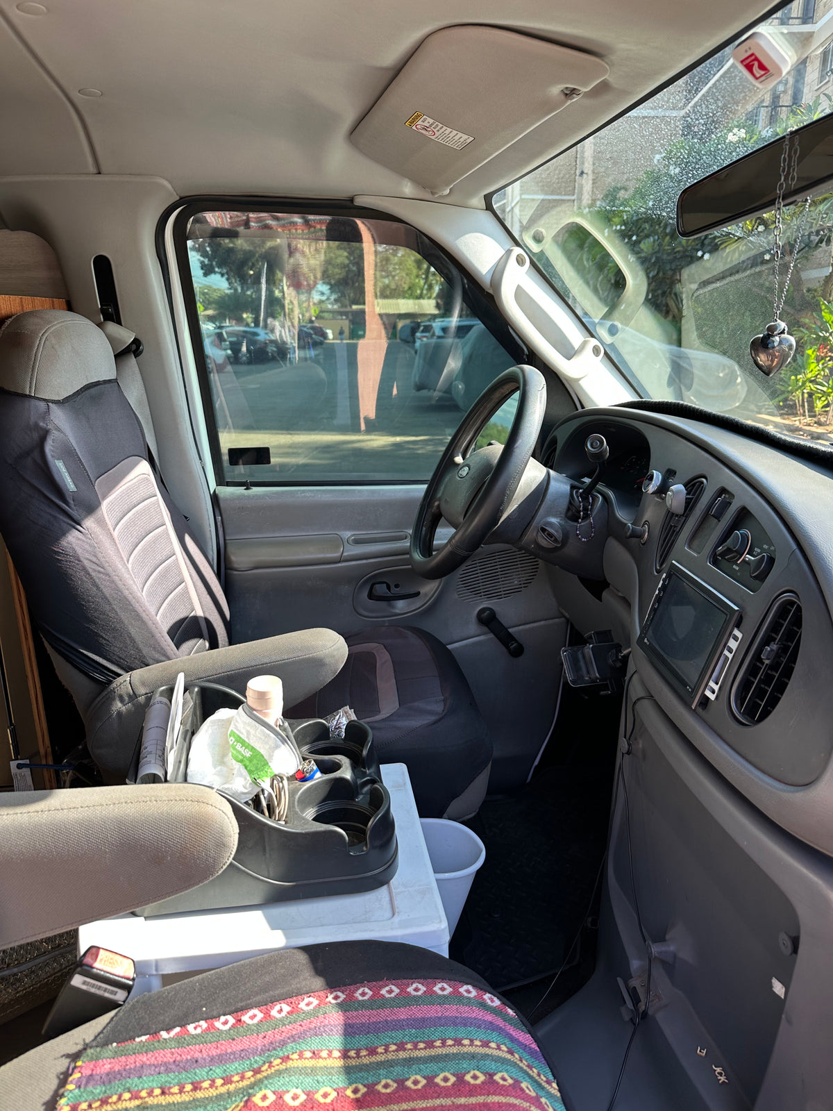 Interior view of an rv rental van, showcasing the driver's seat, dashboard, and custom console with storage. Ready for travel. — photo 8