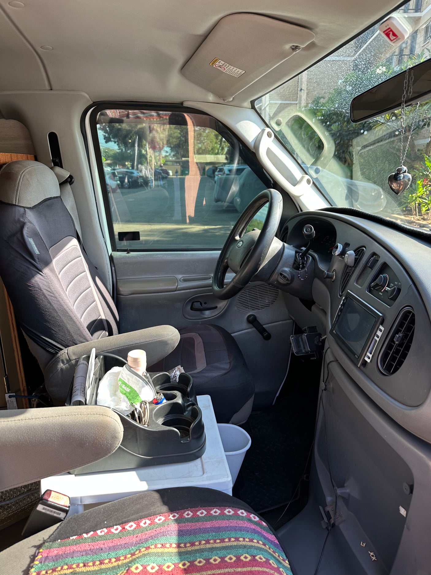 Interior view of an rv rental van, showcasing the driver's seat, dashboard, and custom console with storage. Ready for travel.