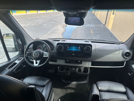 Driver's perspective of a Mercedes-Benz rv rental's spacious interior, showing dashboard, steering wheel, and infotainment screen.