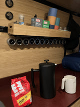 RV rental kitchenette with coffee, tea, and magnetic spices. Features a French press, colorful cups, and gauges, ideal for van life.