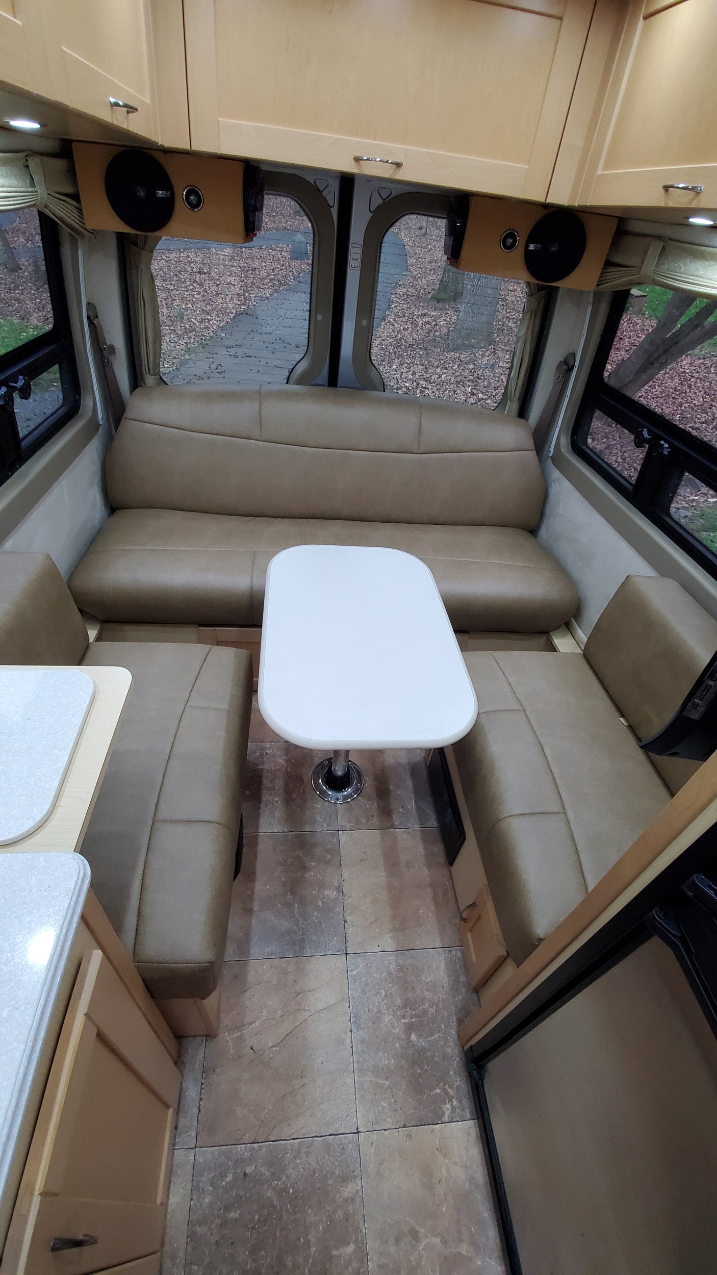 Spacious RV rental interior featuring comfortable dinette seating, a white table, and overhead cabinets for a cozy trip.