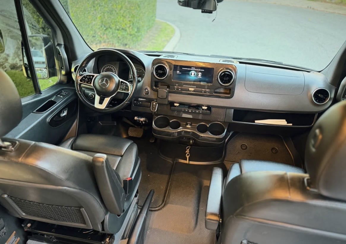 Spacious Mercedes-Benz RV rental interior with black leather seats, modern dashboard, and carbon fiber accents. — photo 13
