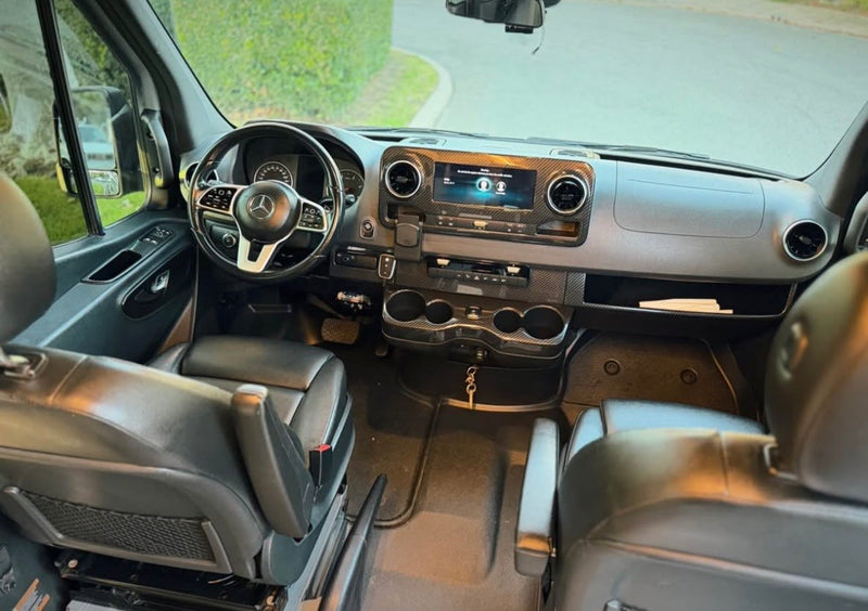 Spacious Mercedes-Benz RV rental interior with black leather seats, modern dashboard, and carbon fiber accents. — photo 13