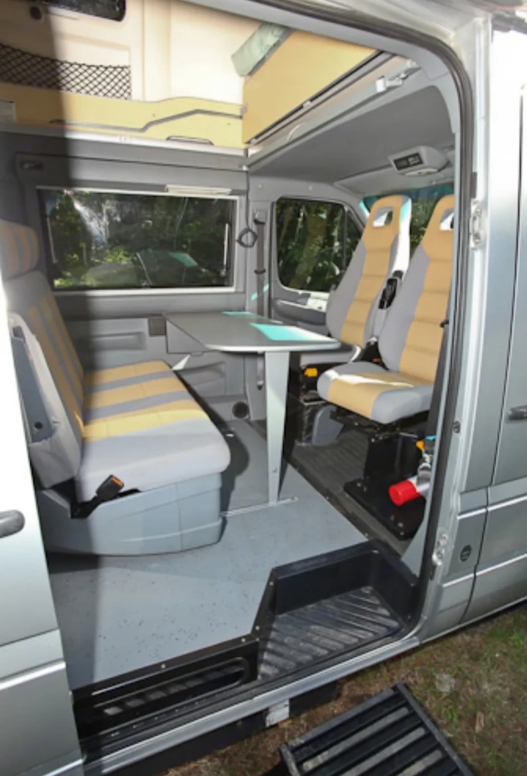 RV rental interior: A dining area with a table, a long bench seat on the left, and front seats rotated to face the rear. — photo 2