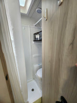 Compact RV rental wet bath, combining shower and toilet for efficient use of space, with hooks and storage.