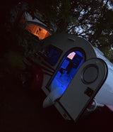 Cozy night camping in RV rental. Two teardrop trailers illuminate the darkness, one blue, one orange.