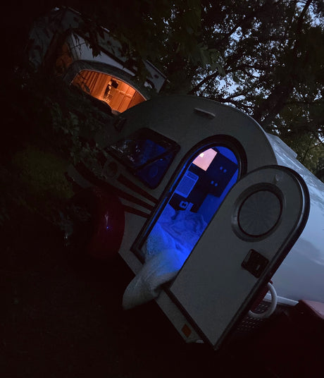 Cozy night camping in RV rental. Two teardrop trailers illuminate the darkness, one blue, one orange.