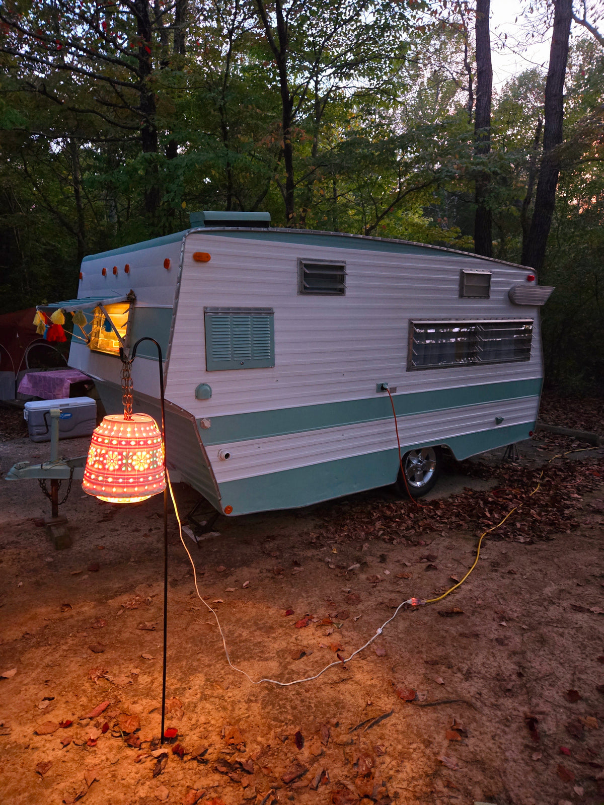Enjoy a cozy evening in a vintage RV rental. This retro camper is nestled in a forest, illuminated by a glowing lantern. — photo 6