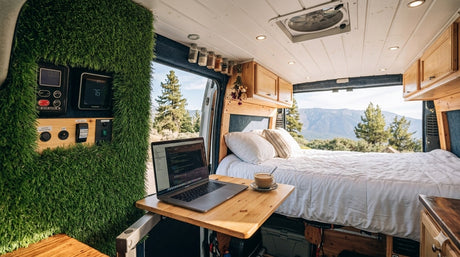 Unique RV rental interior: A cozy camper van features a bed, laptop workspace, faux grass wall, and mountain views.