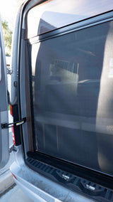 Rear screen door of an rv rental van, offering ventilation while showing glimpses of the interior seating.
