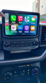 Inside your rv rental, see the modern car interior's dashboard with Apple CarPlay showing apps and climate controls illuminated.